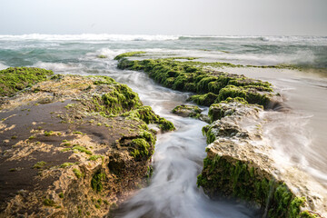 Ethereal Long Exposure Seascape of Dynamic Ocean Water Cascading Over Ancient Moss-Covered Rock Formations Along a Rugged Coastline