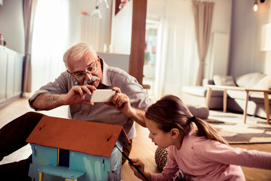 Senior grandfather and child granddaughter focused on craft project at home