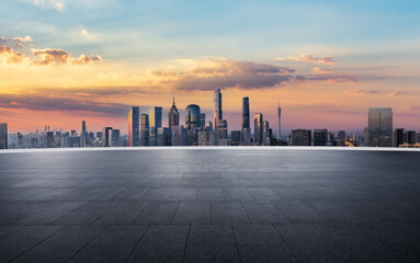 Empty square floor and city skyline with modern commercial buildings at beautiful sunrise in...