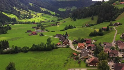 Aerial view of houses nestled in a green valley, a tapestry of nature's hues, where the architecture complements the idyllic landscape, Lake Brienz, Canton of Bern, Switzerland.