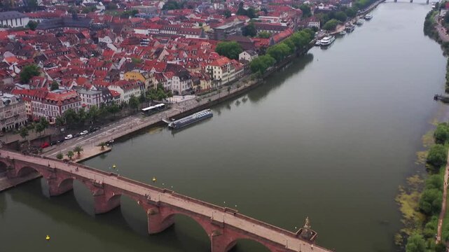 Aerial view of the Alte Brucke bridge over the Neckar River with old town buildings and boats docked along the river, Heidelberg, Baden-Wurttemberg, Germany.