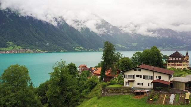 Aerial view of the turquoise waters of Lake Brienz meeting the quaint village of iseltwald with red-roofed houses, Lake Brienz, Canton of Bern, Switzerland.