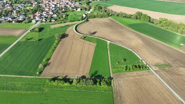 Aerial view of the landscape with its patchwork of fields, winding roads, and a quaint village with red-roofed houses, Wittenheim, Grand Est, France.