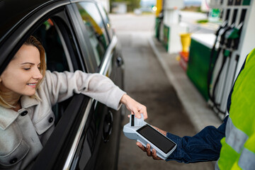 Woman paying for gas fueling car with credit card