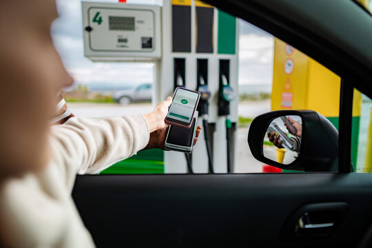 Woman paying for gas using smartphone contactless payment