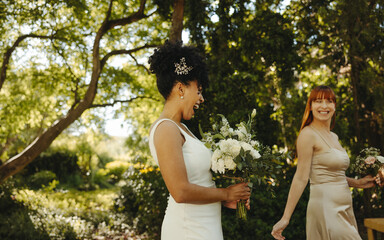 Joyful bridesmaids celebrating in a sunny green garden during a wedding event