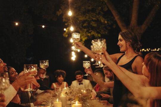 Intimate wedding celebration with friends toasting outdoors under lights