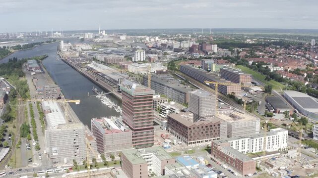 Aerial view of the Bremen waterfront showcasing a mix of modern buildings, a river, and industrial areas under a bright sky, Bremen, Bremen, Germany.