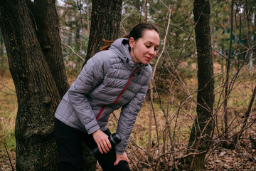 A young woman is resting after a run in the forest. Breathing after exercise