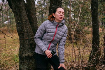 A young woman is resting after a run in the forest. Breathing after exercise
