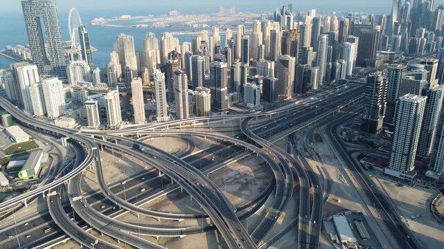 Aerial view of a complex highway interchange cutting through the urban landscape, contrasting concrete with the glass and steel of the city, Dubai, Dubai, United Arab Emirates.