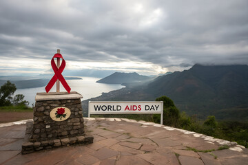 World AIDS Day monument with red ribbon and rose plaque overlooking water and mountains under cloudy sky. generative ai