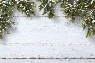 Christmas background with fir tree branches and snow on white wooden board