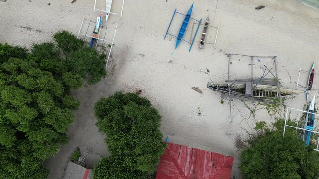 Aerial view of boats resting on the sandy beach, showcasing the vibrant contrast between the turquoise water and the white sand, Panglao, Central Visayas, Philippines.