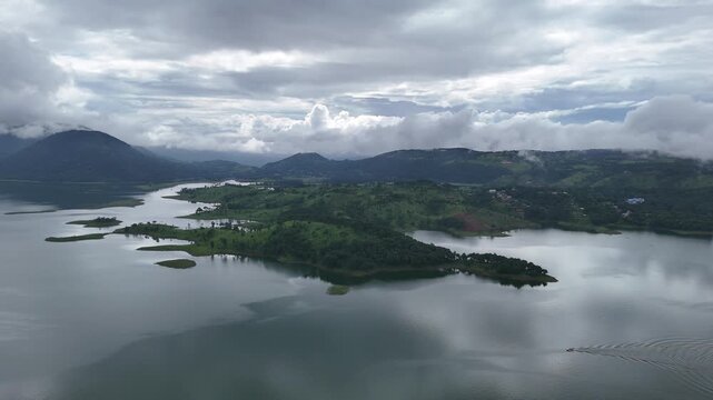 Aerial view of a serene Umiam Lake reflecting the cloudy sky, surrounded by lush green hills, Shillong, Meghalaya, India.