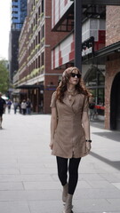 Fototapeta premium Stylish woman walking in the city wearing sunglasses and beige outfit