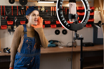 Craftsman or artisan blogger with ring light and smartphone streaming in workshop with assortment tools loud news or sale. Blogging, industry and technology