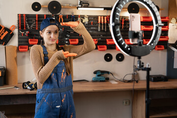 Craftsman or artisan blogger with ring light and smartphone streaming in workshop with assortment...