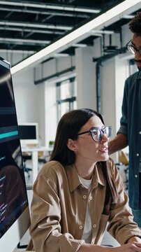 asian developer coding at desktop with large monitor, pair programming with colleague, lines of code visible