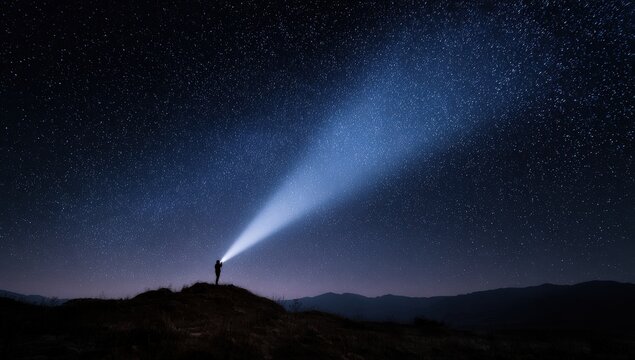Lone figure on a hill illuminates the starry night sky with a bright beam - Powered by Adobe