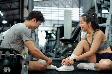 Fitness couple or friend having rest and talking, drinking water at gym
