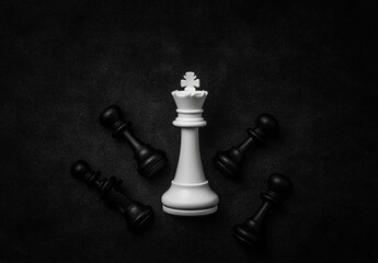 White King Chess Piece Surrounded by Black Pawns on Dark Surface