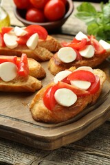 Tasty bruschettas with mozzarella cheese and tomatoes on wooden table, closeup