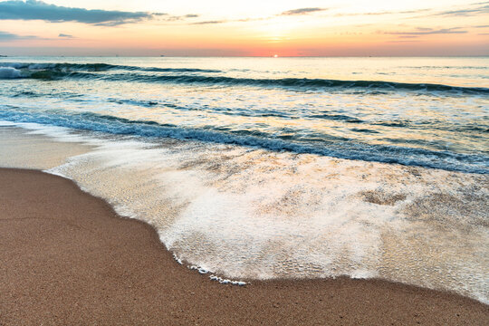 Sunrise on a white sand beach with waves in Balne&aacute;rio Cambori&uacute;, Santa Catarina, Brazil.
