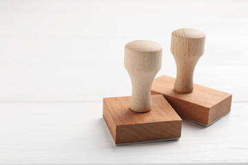 Two wooden stamps on white table, closeup. Space for text