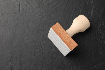 One wooden stamp on dark textured table, top view. Space for text