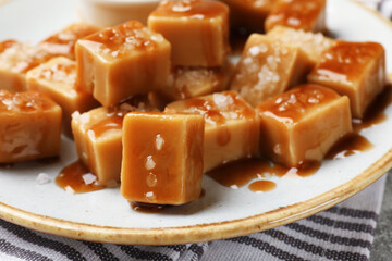 Tasty candies with salt and caramel sauce on table, closeup