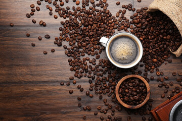 Aromatic coffee in cup, beans and grinder on wooden table, flat lay. Space for text