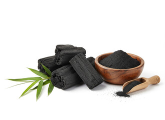 natural composition features several pieces of black charcoal chunks and a wooden bowl filled with fine black charcoal powder. A small wooden scoop holds more powder, and fresh green bamboo leaves add