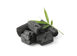 natural composition features several pieces of black charcoal chunks and a wooden bowl filled with fine black charcoal powder. A small wooden scoop holds more powder, and fresh green bamboo leaves add