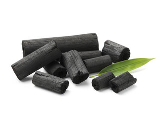 natural composition features several pieces of black charcoal chunks and a wooden bowl filled with fine black charcoal powder. A small wooden scoop holds more powder, and fresh green bamboo leaves add