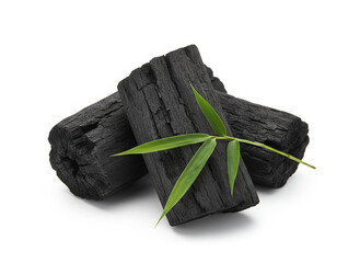 natural composition features several pieces of black charcoal chunks and a wooden bowl filled with fine black charcoal powder. A small wooden scoop holds more powder, and fresh green bamboo leaves add
