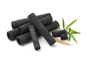 natural composition features several pieces of black charcoal chunks and a wooden bowl filled with fine black charcoal powder. A small wooden scoop holds more powder, and fresh green bamboo leaves add