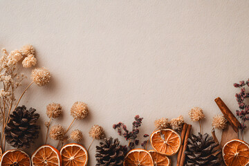 Natural boho Christmas border with dried oranges, cinnamon, and pine cones on beige craft paper