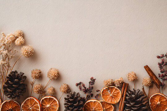 Natural boho Christmas border with dried oranges, cinnamon, and pine cones on beige craft paper