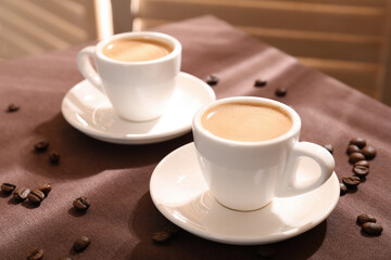 Aromatic coffee in cups and beans on table, closeup