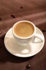 Aromatic coffee in cup and beans on table, closeup