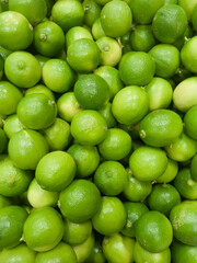 A stack of green lemons piled on a supermarket shelf