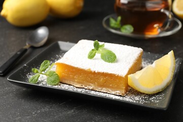 Tasty lemon bar with mint, fresh fruits and tea on black table, closeup