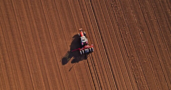 Aerial view of tractor sowing seeds in a plowed field
