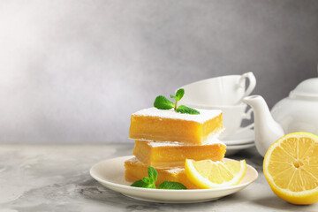 Tasty lemon bars with mint and fresh fruits on grey marble table, closeup. Space for text