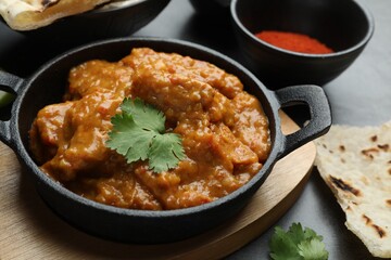 Delicious chicken tikka masala, cilantro, lavash and paprika powder on grey textured table, closeup