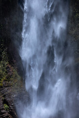Water cascading down of a tall waterfall forming a curtain of water. Selective focus, Long exposure shot. 