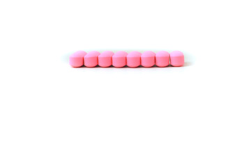 Pink pills lined up on a clean white surface representing medication treatment