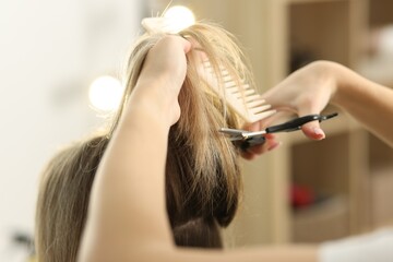 Fototapeta premium Hairdresser cutting woman's hair in salon, closeup