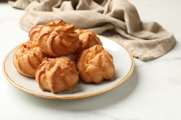 Fresh tasty profiteroles on white marble table, closeup